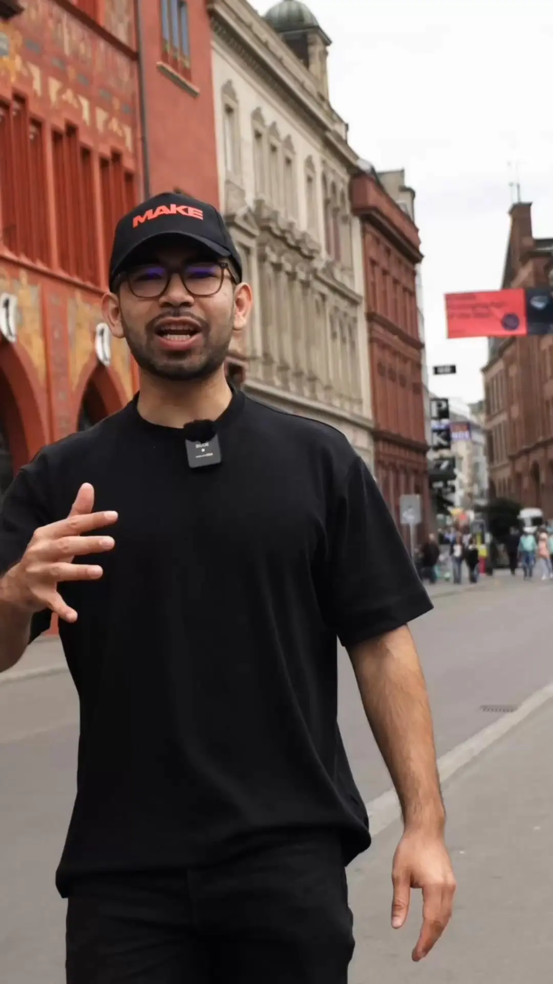 Standbild aus der Video-Anzeige von MAKE: Sprecher mit MAKE-Kappe in der Basler Altstadt