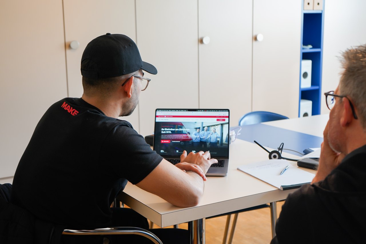 Zwei Männer betrachten einen Laptop auf einem Schreibtisch in einem Büro