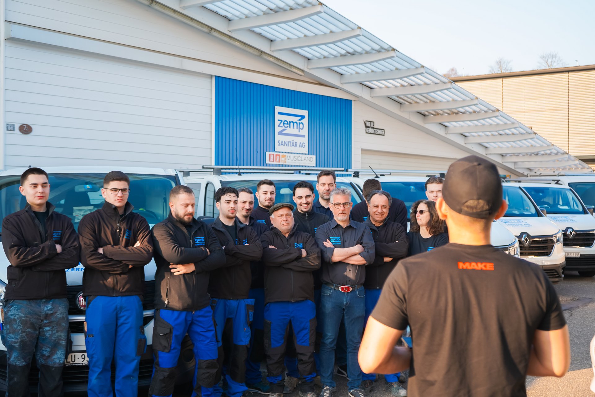 Team eines Handwerksbetriebs vor den Firmenfahrzeugen