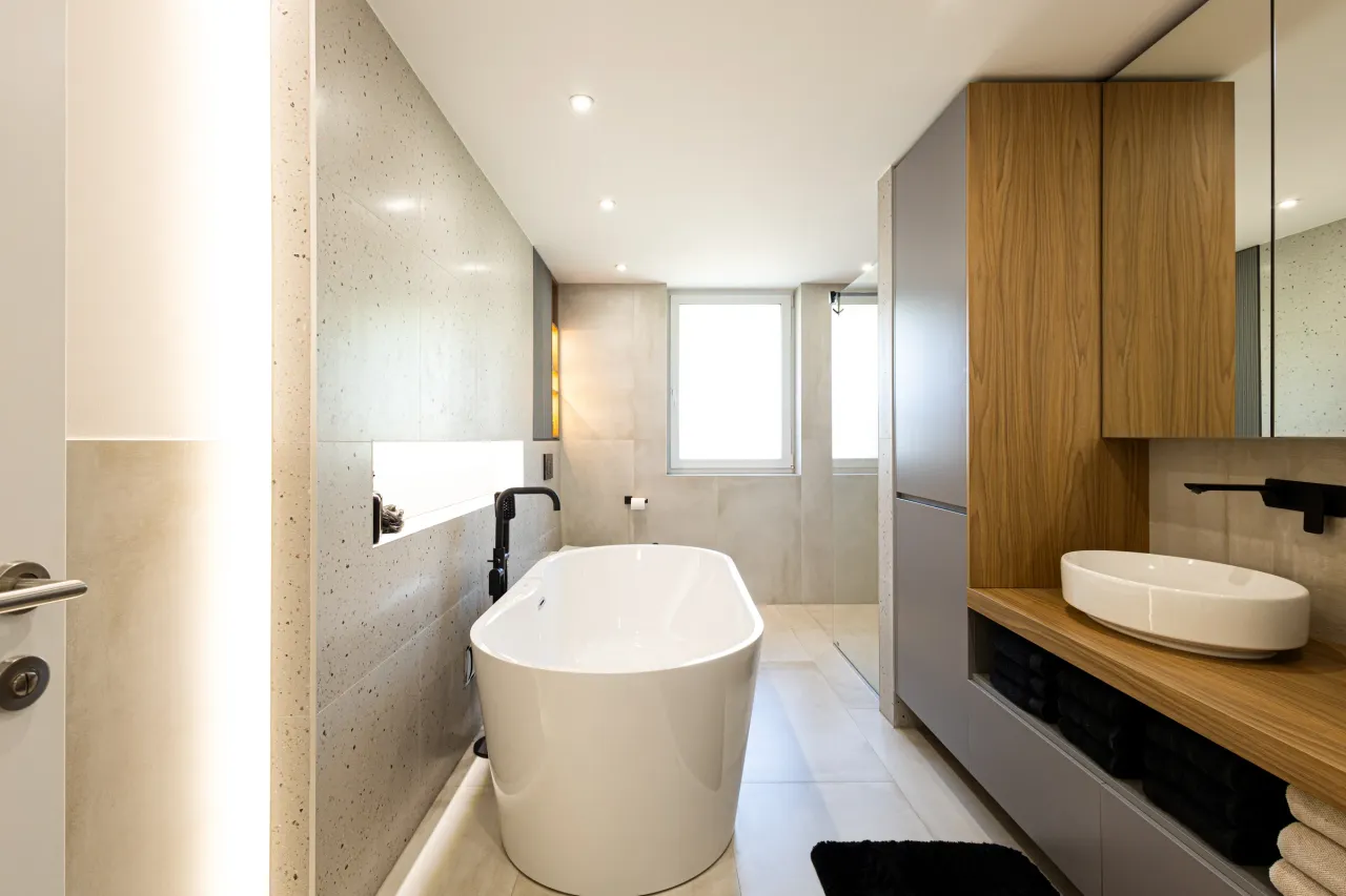 Bad mit freistehender Wanne, Terrazzo-Wand und Hochschrank in Nussbaum