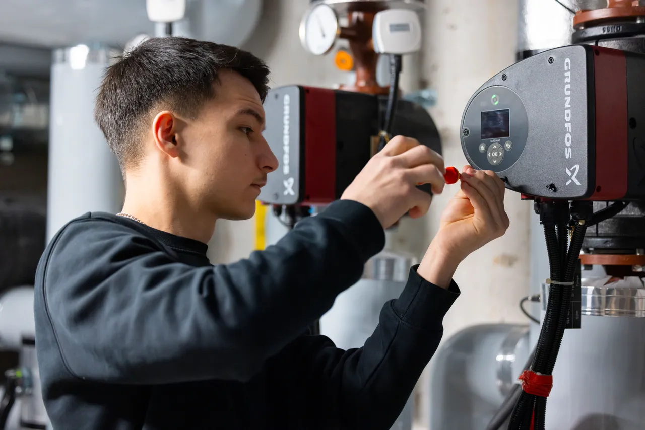 Elektriker stellt im Heizungsraum eine Umwälzpumpe ein
